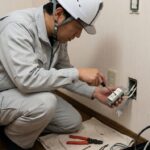 コンセントの工事をしている電気工事士の画像