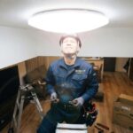 ledシーリングライトを見上げる電気工事士の画像