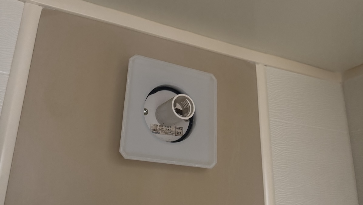 台座が割れてカバーを付けられなくなった浴室照明。四角い白い台座の中央に、電球を差し込むソケットがむき出しになっている(交換前)